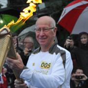 Sir Bobby Charlton receives the flame.