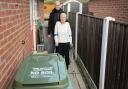 Robert and Philomena Mccallum outside the bungalow with the green bin in the foreground
